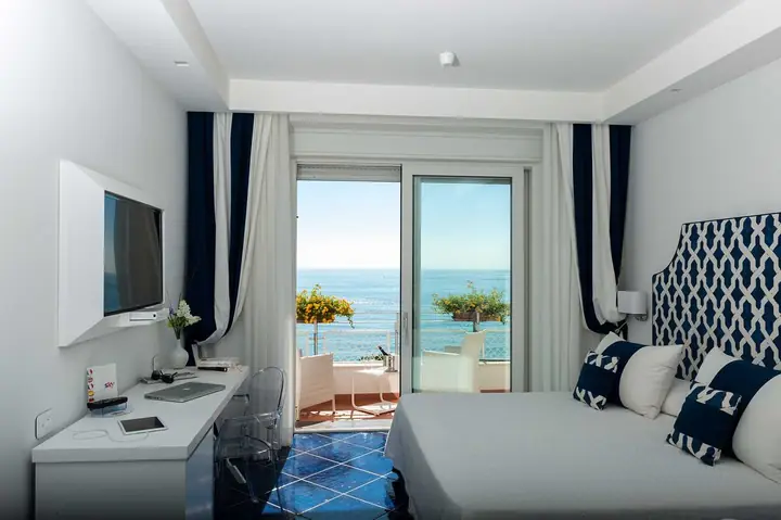 Una camera in bianco e blu con la portafinestra aperta sul mare